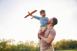 Father is holding son that playing ,,with ,toy plane photo