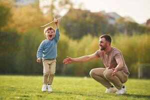 Weekend, activities. Playing with toy plane. Happy father with son are having fun on the field at summertime photo