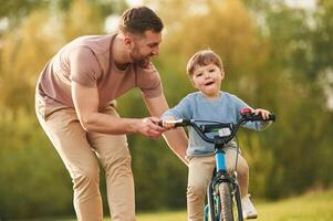Riding on the blue ,bicycle. Happy ,father with son are having fun on the field at summertime photo