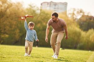 Summertime happiness.. Running with toy ,plane. Father with son are having fun on the field photo