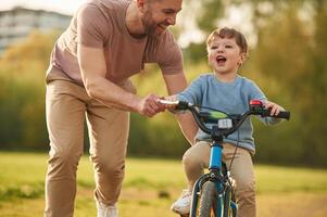 Blue, bicycle, riding,. Happy father with son are having fun on the field at summertime photo