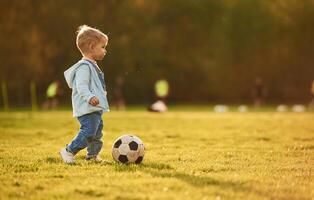 Playing ,with soccer ball. Cute happy little boy is on the field outdoors photo