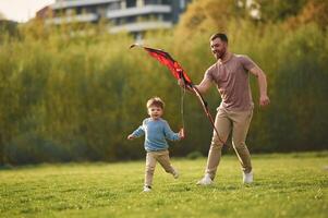 Red kite. Happy, father with son are having fun on the field at summertime photo