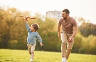 Summertime happiness.. Running with t,oy, plane. Father with son are having fun on the field photo
