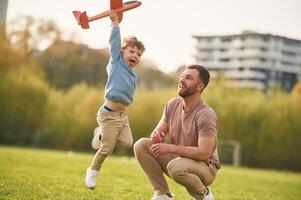Freedom, playing,, with toy plane. Happy father with son are having fun on the field at summertime photo