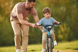 Blue, bicycle,, riding. Happy father with son are having fun on the field at summertime photo