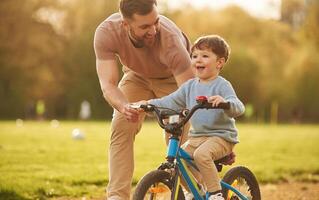 Blue bicycle, ,,riding. Happy father with son are having fun on the field at summertime photo