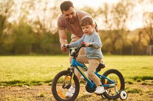 Blue ,bicycle, riding. Happy father with son are having fun on the field at summertime photo