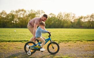 With ,bicycle, having ,fun. Happy father with son are on the field at summertime photo