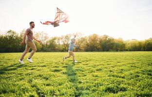 Red ,kite. Happy father with son are having fun on the field at summertime photo