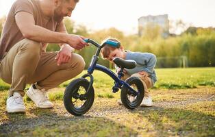 Bicycle,, having fun. Happy father with son are on the field at summertime photo