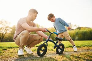 Bicycle, having ,fun. Happy father with son are on the field at summertime photo