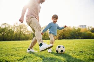 Playing soccer. Happy ,father with son are having fun on the field at summertime photo