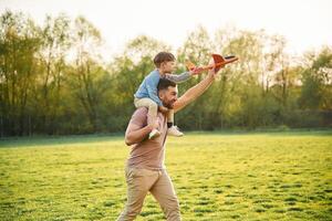 Orange ,colored ,toy plane, playing. Happy father with son are having fun on the field at summertime photo