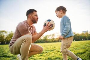 With, soccer ,ball. Happy father with son are having fun on the field at summertime photo