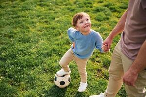 Game of soccer. .With ball. Happy father with son are having fun on the field at summertime photo