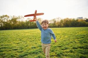 Running, with toy plane. Cute happy little boy is on the field outdoors photo
