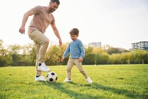 Playing soccer.. Happy father with son are having fun on the field at summertime photo