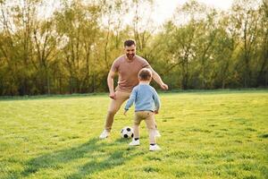Playing,, soccer. Happy father with son are having fun on the field at summertime photo