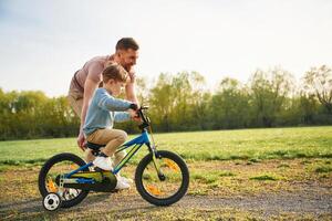 With, bicycle, having fun. Happy ,,father with son are on the field at summertime photo