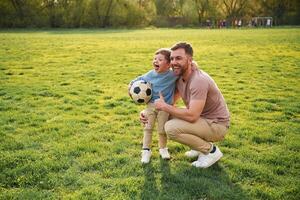 With,, soccer ball. Happy father with son are having fun on the field at summertime photo