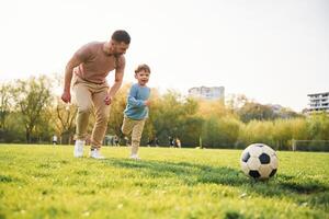 Playing ,soccer. Happy father with son are having fun on the field at summertime photo