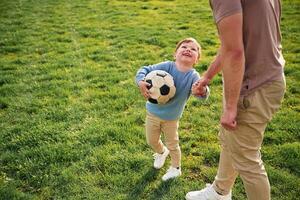Game ,of soccer. With ball. Happy father with son are having fun on the field at summertime photo