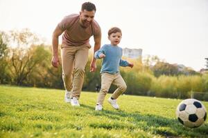 Game, of soccer. With ball. Happy father with son are having fun on the field at summertime photo