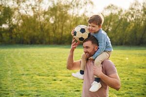 With, soccer ball. Happy father with son are having fun on the field at summertime photo