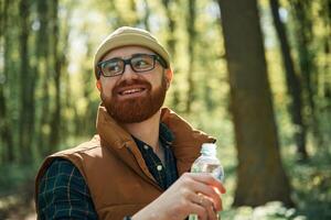 Drinking a water,,. Bearded ,man is in the forest at daytime photo