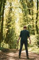 Looks, up, holding, an, axe. Bearded man is in the forest at daytime photo