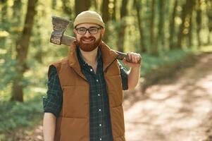 Woodcutter is standing... Bearded man is in the forest at daytime photo