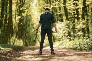Looks up, holding an axe. ,,Bearded man is in the forest at daytime photo