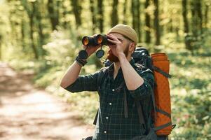 Discovering ,new place with binoculars... Bearded man is in the forest at daytime photo