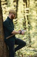 Woodcutter ,is ,standing. Bearded man is in the forest at daytime photo