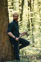 Woodcutter, is standing. Bearded man is in the forest at daytime photo