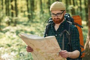 Focused, on, reading the map. Bearded, man is in the forest at daytime photo