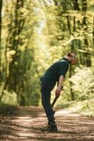 Looks ,up, holding an axe. Bearded man is in the forest at daytime photo