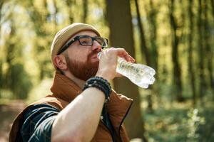 Drinking a water. ,,,Bearded man is in the forest at daytime photo