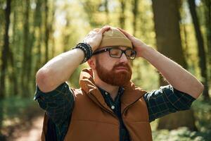 Wearing the hat. Bearded man is in the forest at daytime photo