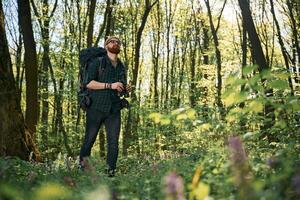 Tourist with binoculars... Bearded man is in the forest at daytime photo