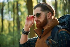 In cool, sunglasses.. Bearded man is in the forest at daytime photo