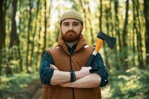 Woodcutter is standing. Bearded ,man ,is in the forest at daytime photo