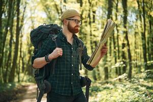 Using the map. Bearded, man ,is in the forest at daytime photo