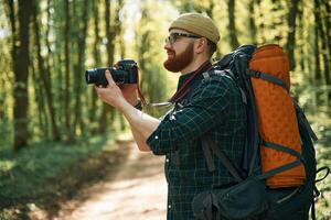 Photographer, with camera. Bearded ,man is in the forest at daytime photo
