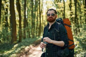 With, backpack. Bearded man is in the forest at daytime photo