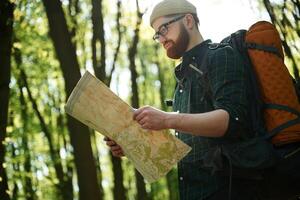 grande papel,, mapa. barbado hombre es en el bosque a tiempo de día foto