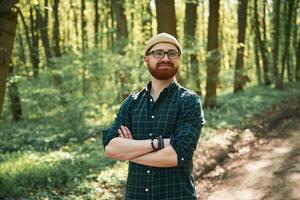 Front, view. Bearded man is in the forest at daytime photo