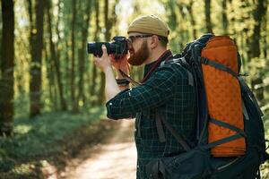 Photographer with ,camera.. Bearded man is in the forest at daytime photo