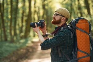 Photographer, with, camera. Bearded man is in the forest at daytime photo